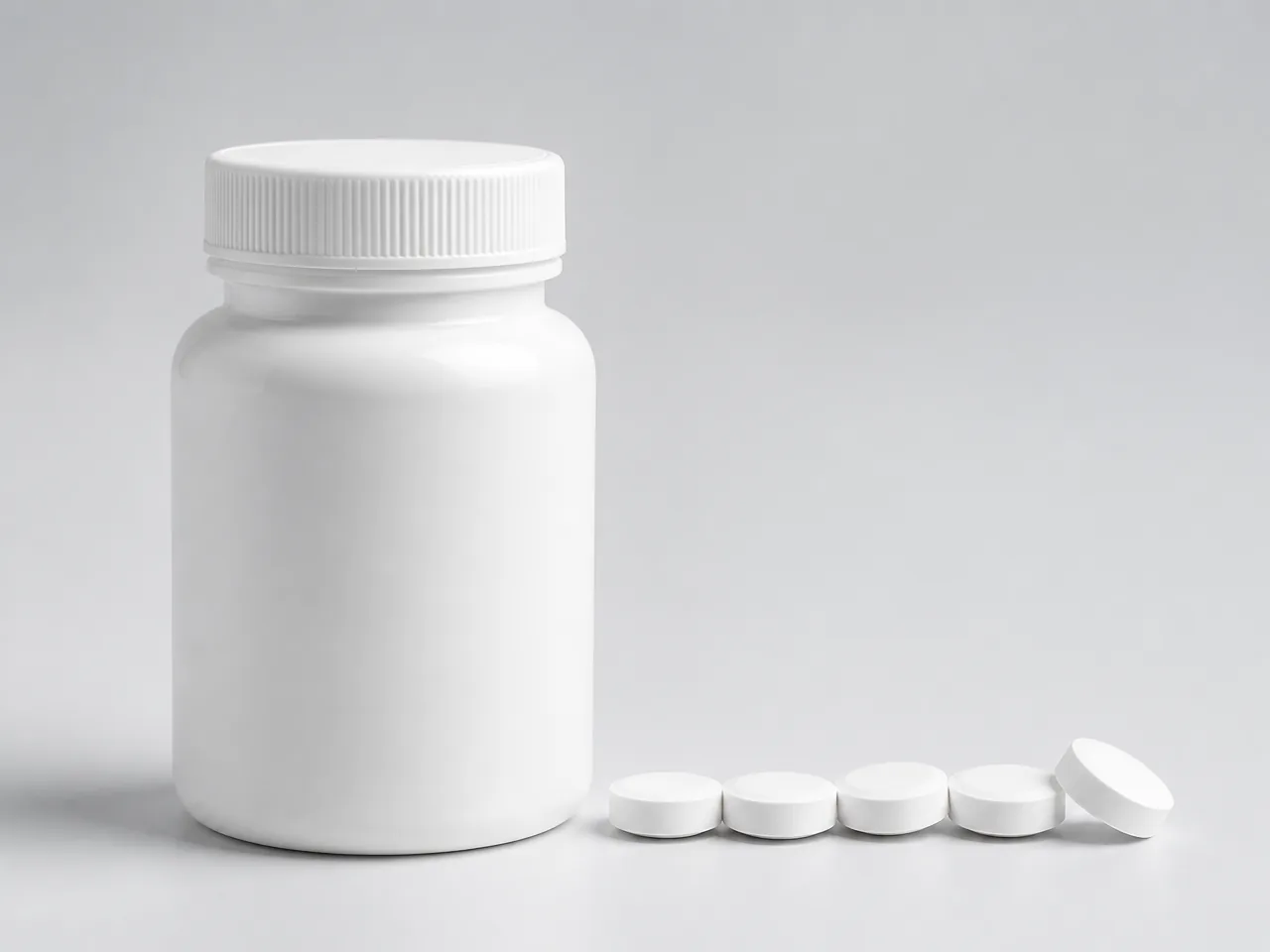 White supplement tablets beside a bottle
